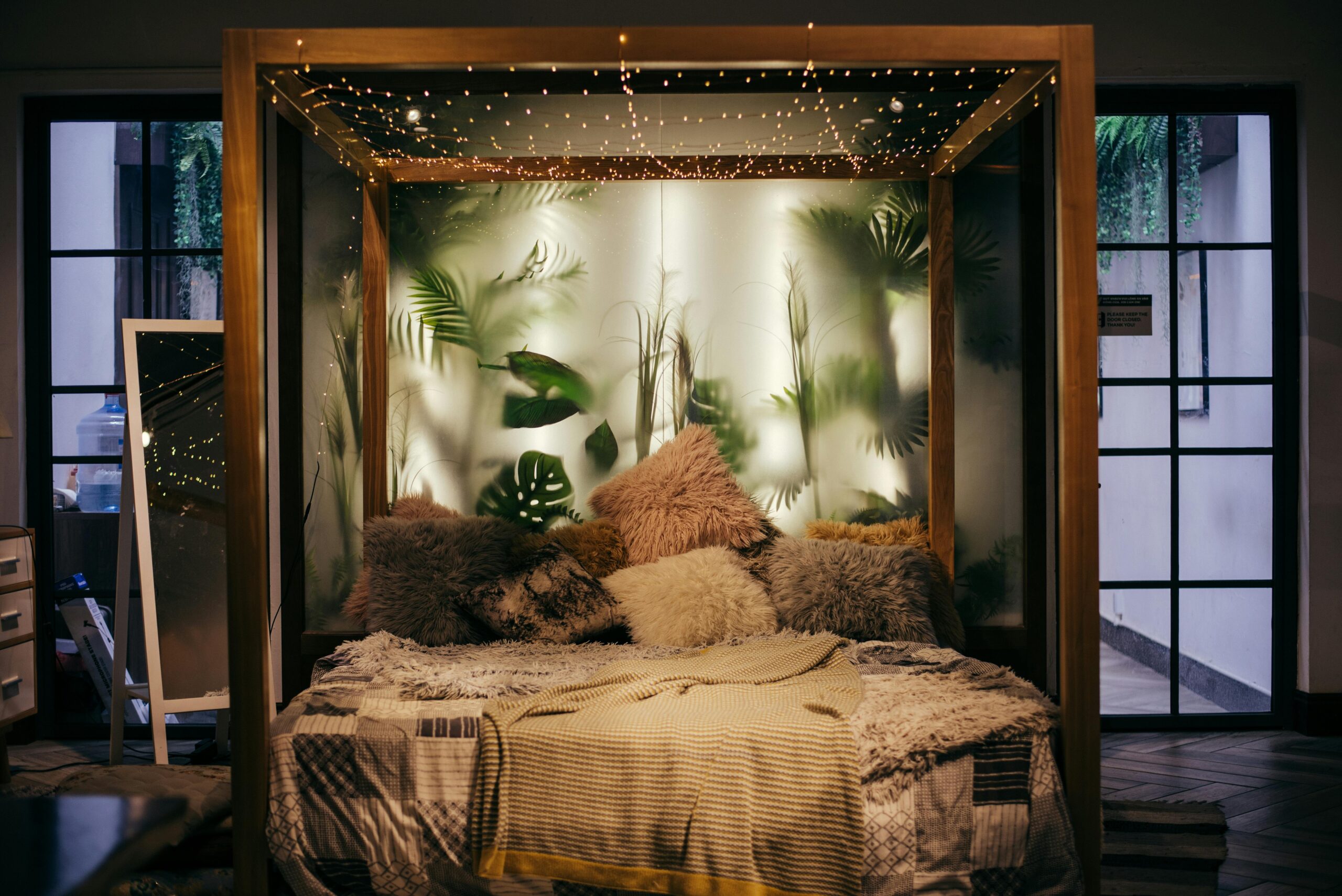 Luxurious modern bedroom with plants and string lights, creating a cozy ambiance.